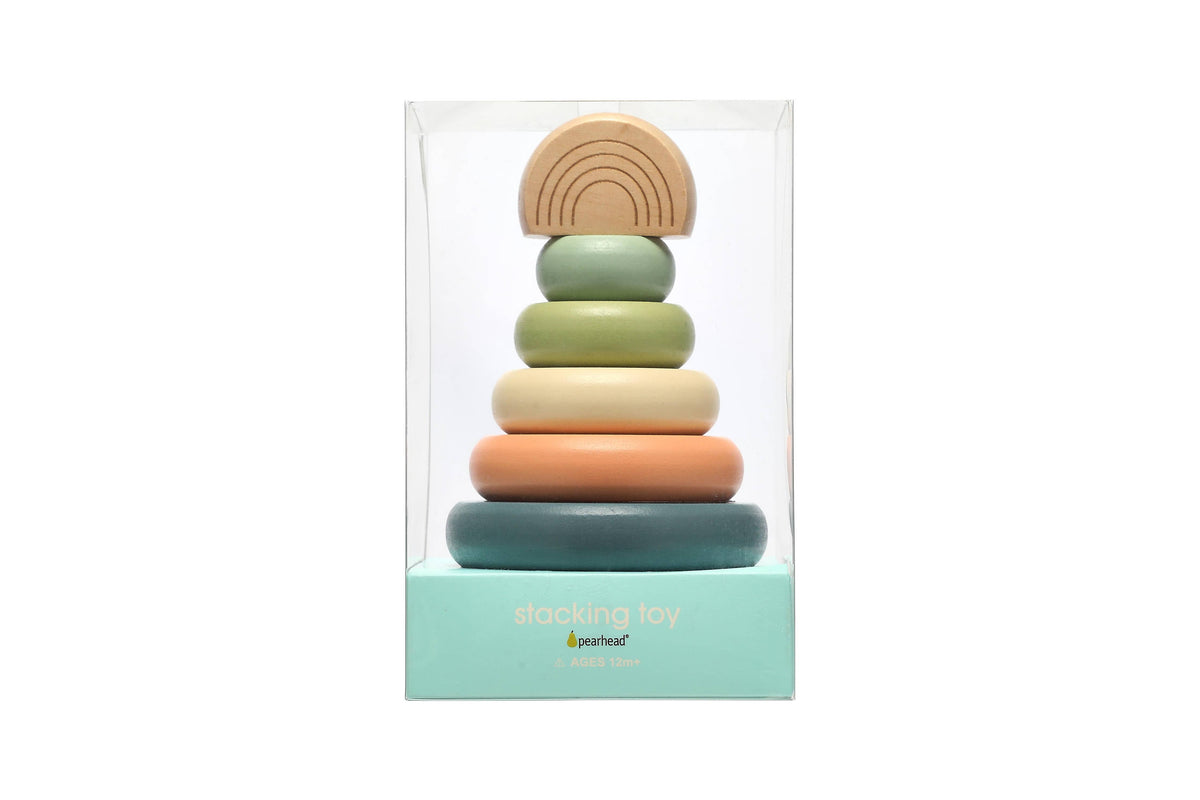 A wooden stacking toy consisting of a peg with five multicolor earth tone rings and a wooden rainbow topper in a plastic pearhead brand gift box on a white background.
