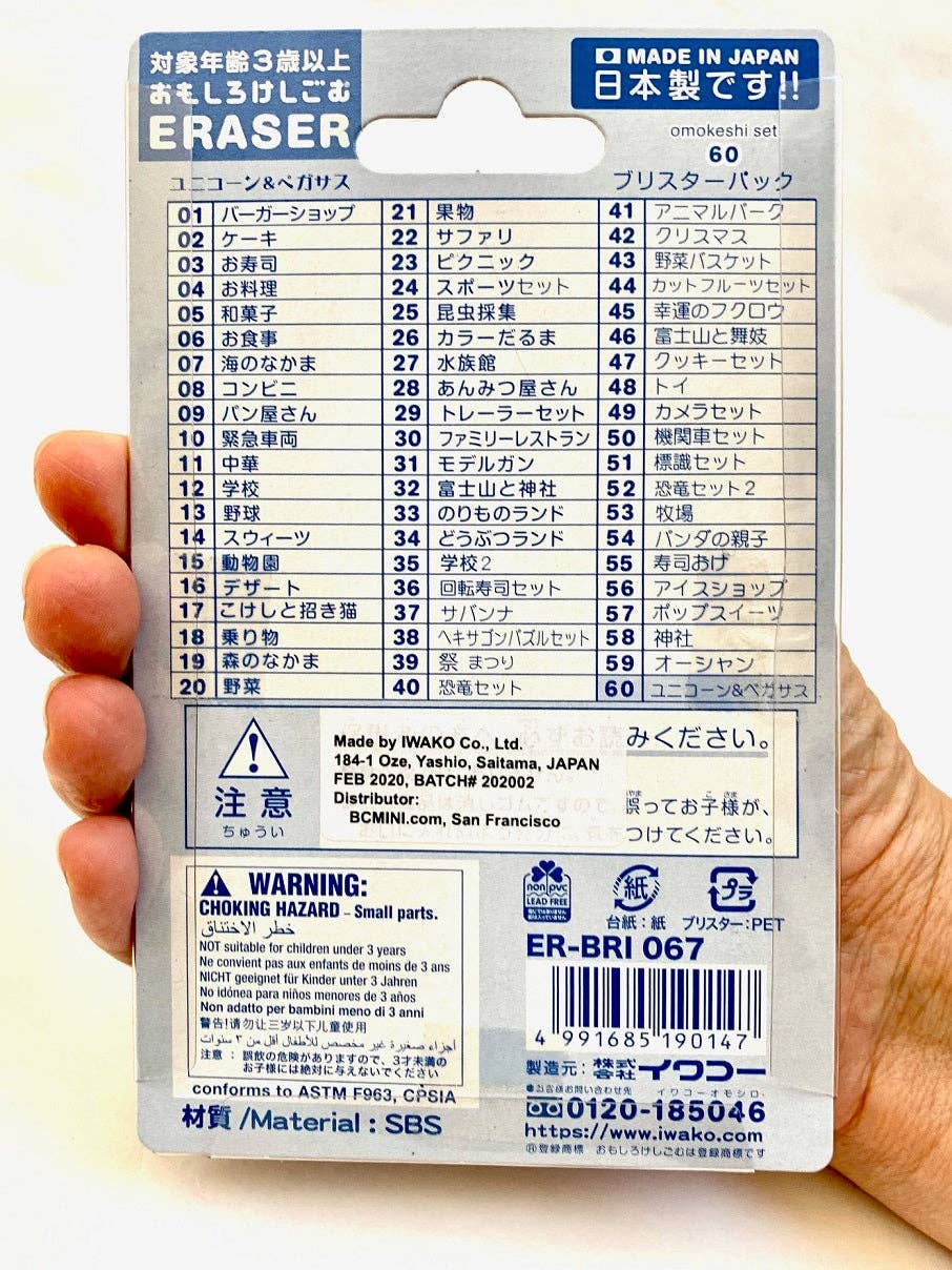 Eraser packaging with Japanese text and a warning label held by a hand.