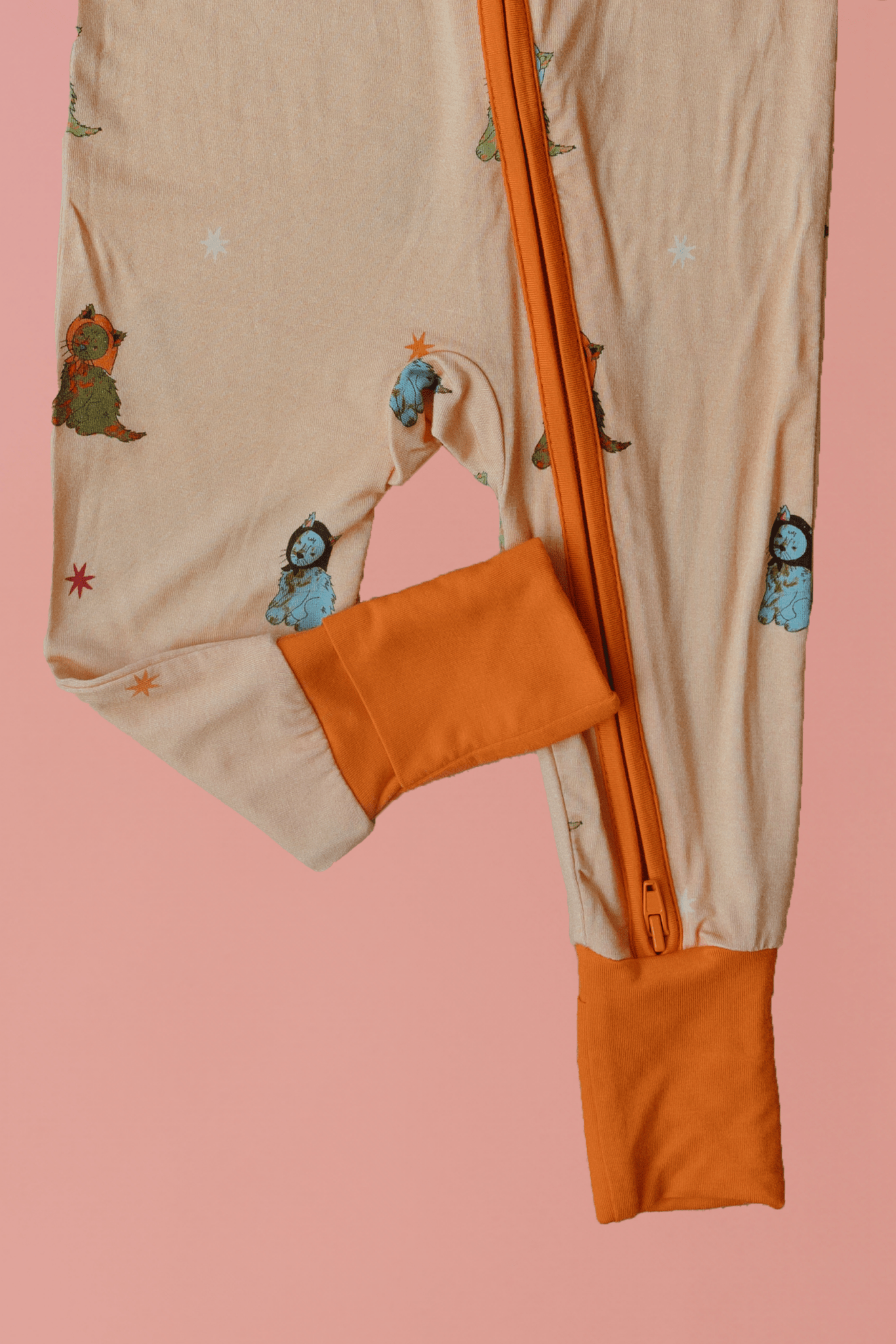 Beige and orange baby romper with cartoon characters on a pink background