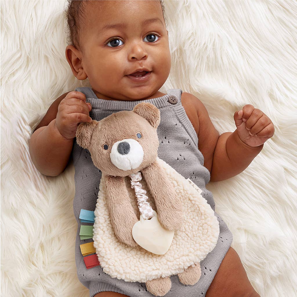 Baby holding a teddy bear toy on a white fluffy surface
