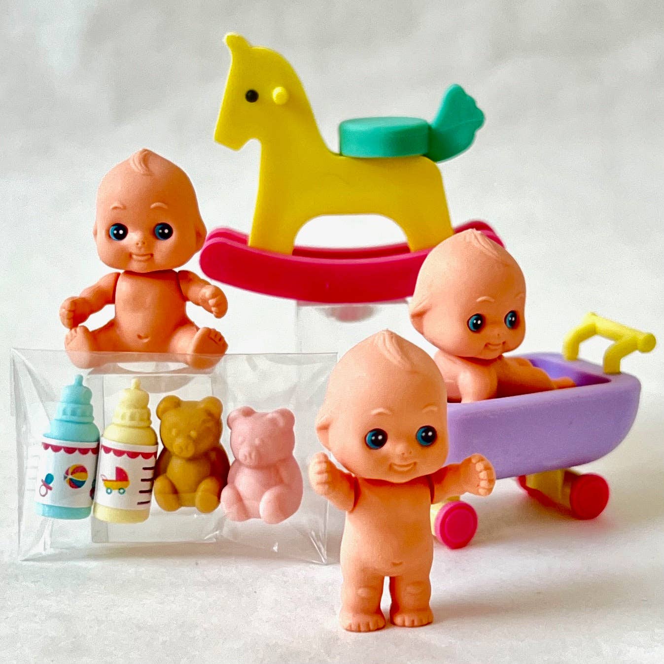Set of colorful baby eraser figurines with toys on a white background