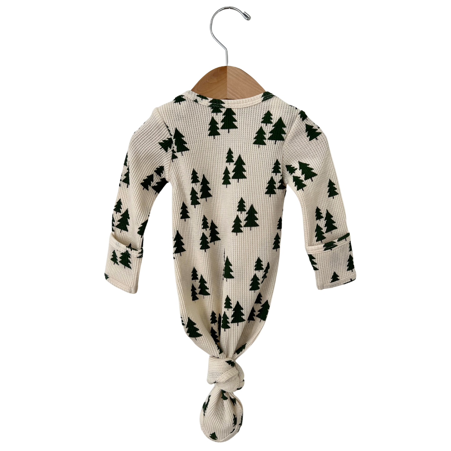 Baby gown with tree pattern on a hanger against a white background