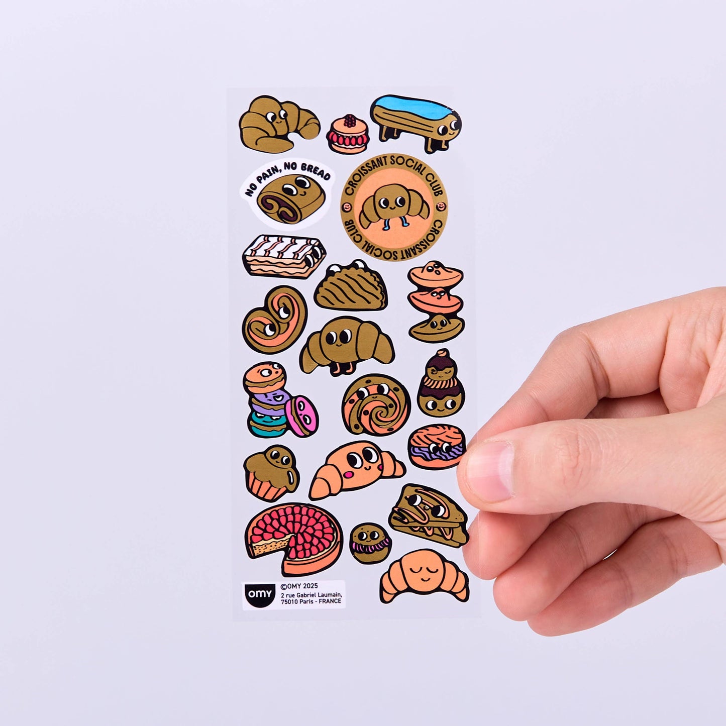 Sheet of cartoon food stickers with a hand holding it on a light gray background