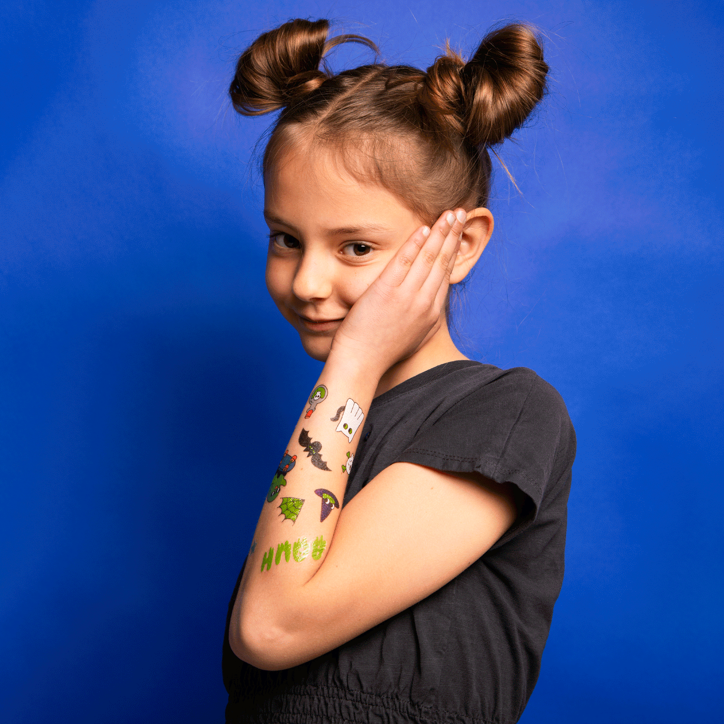 Flashing video of child with temporary tattoos glowing in the dark on their arm against a blue background.