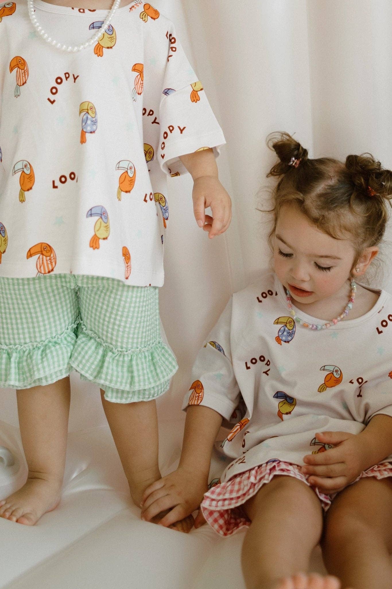 Two children wearing matching shirts with cartoon designs on a white background