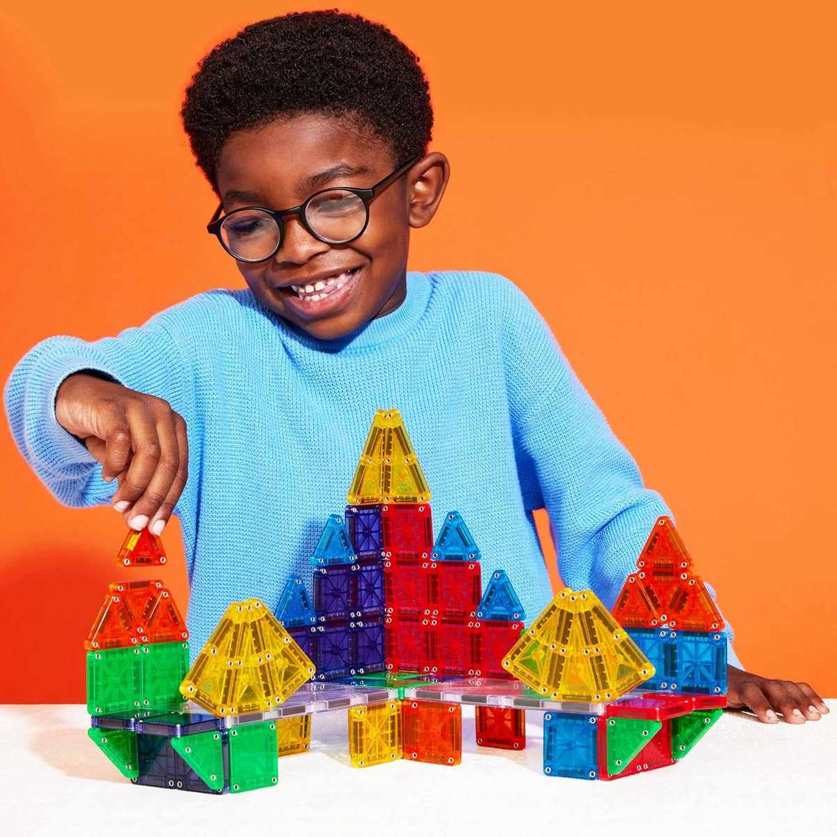 Child playing with colorful building blocks against an orange background