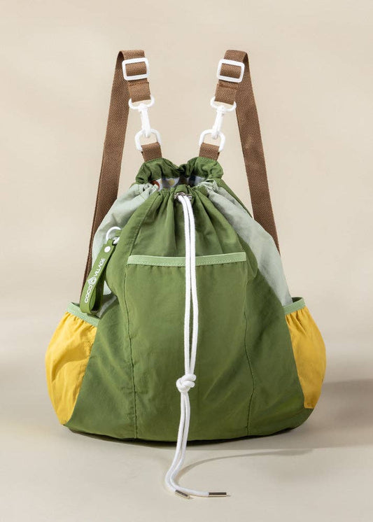 Green and yellow drawstring bag with brown straps on a beige background