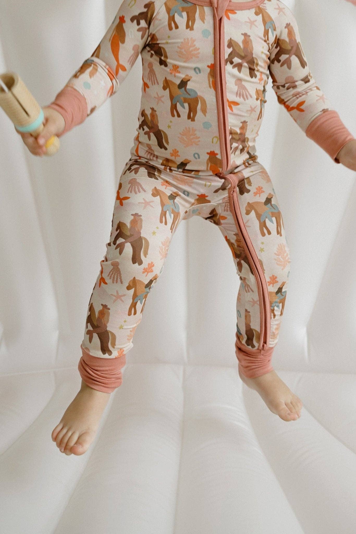 Patterned fabric with horses and mermaids on a pink background