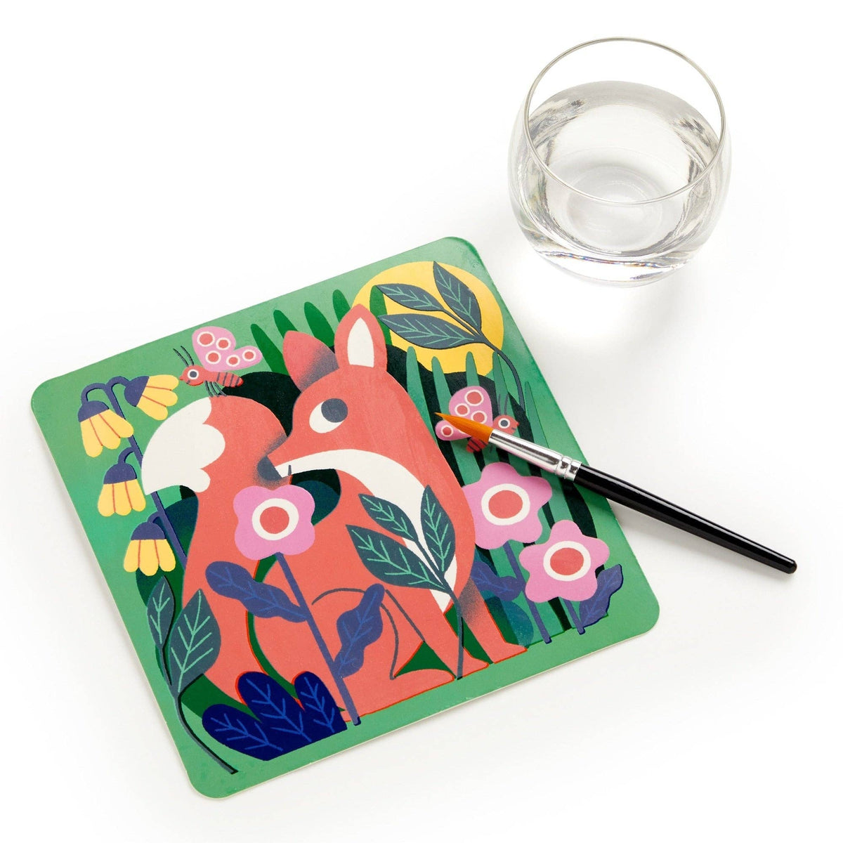 Coloring book with a fox design, pen, and glass of water on a white background