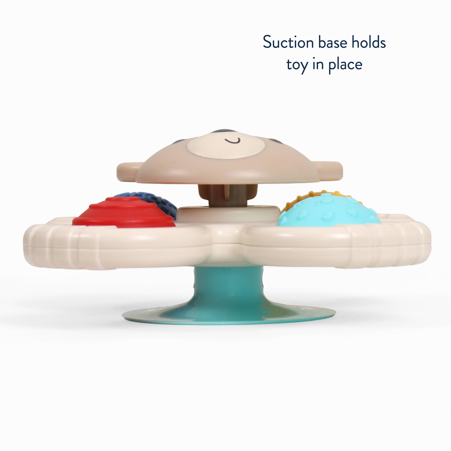 A baby sensory toy with a beige animal head on a teal suction base, featuring textured red, blue, and yellow cups on a white circular platform. Text in the upper right reads 'Suction base holds toy in place'.