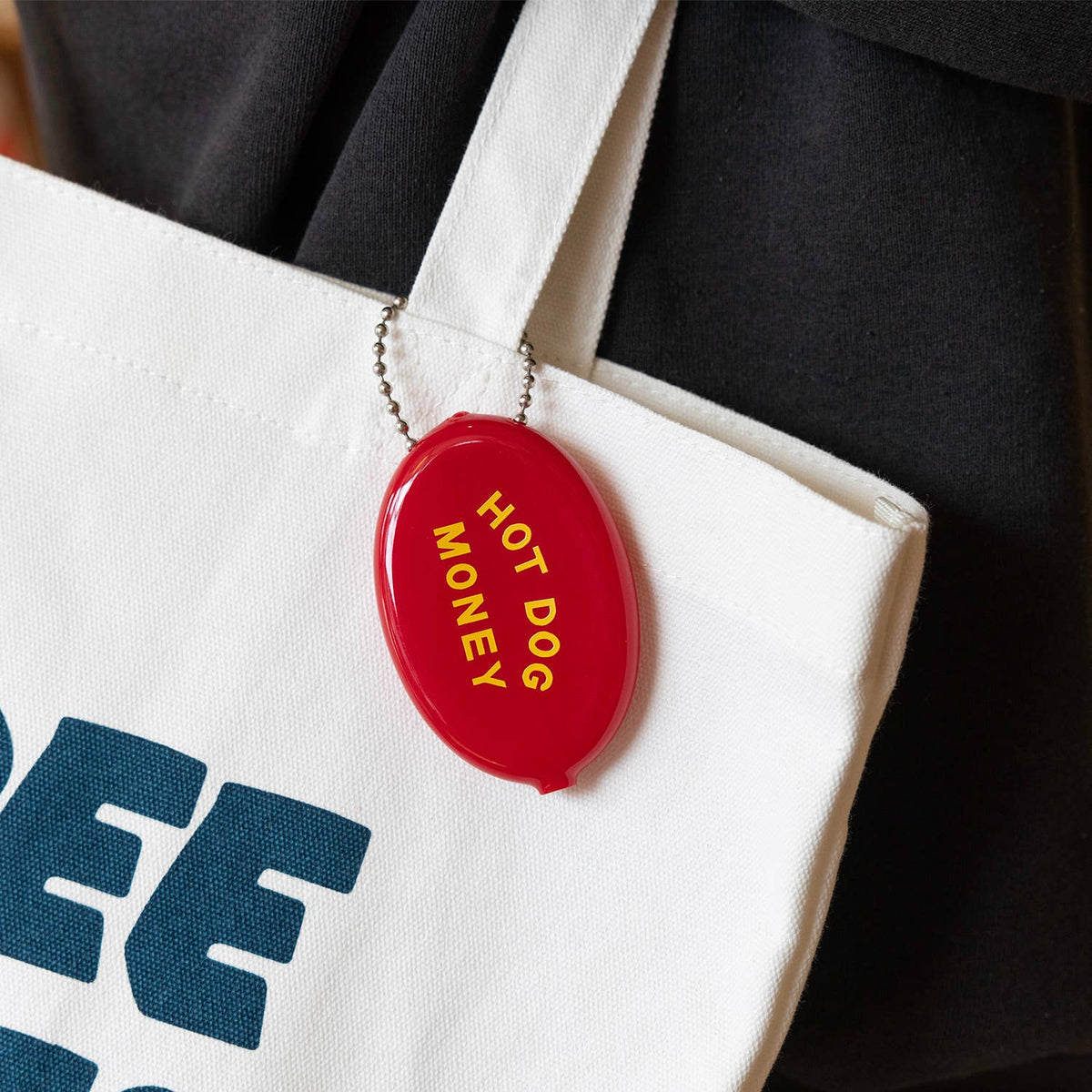 Red 'Hot Dog Money' coin ourse
 on a white tote bag with text.