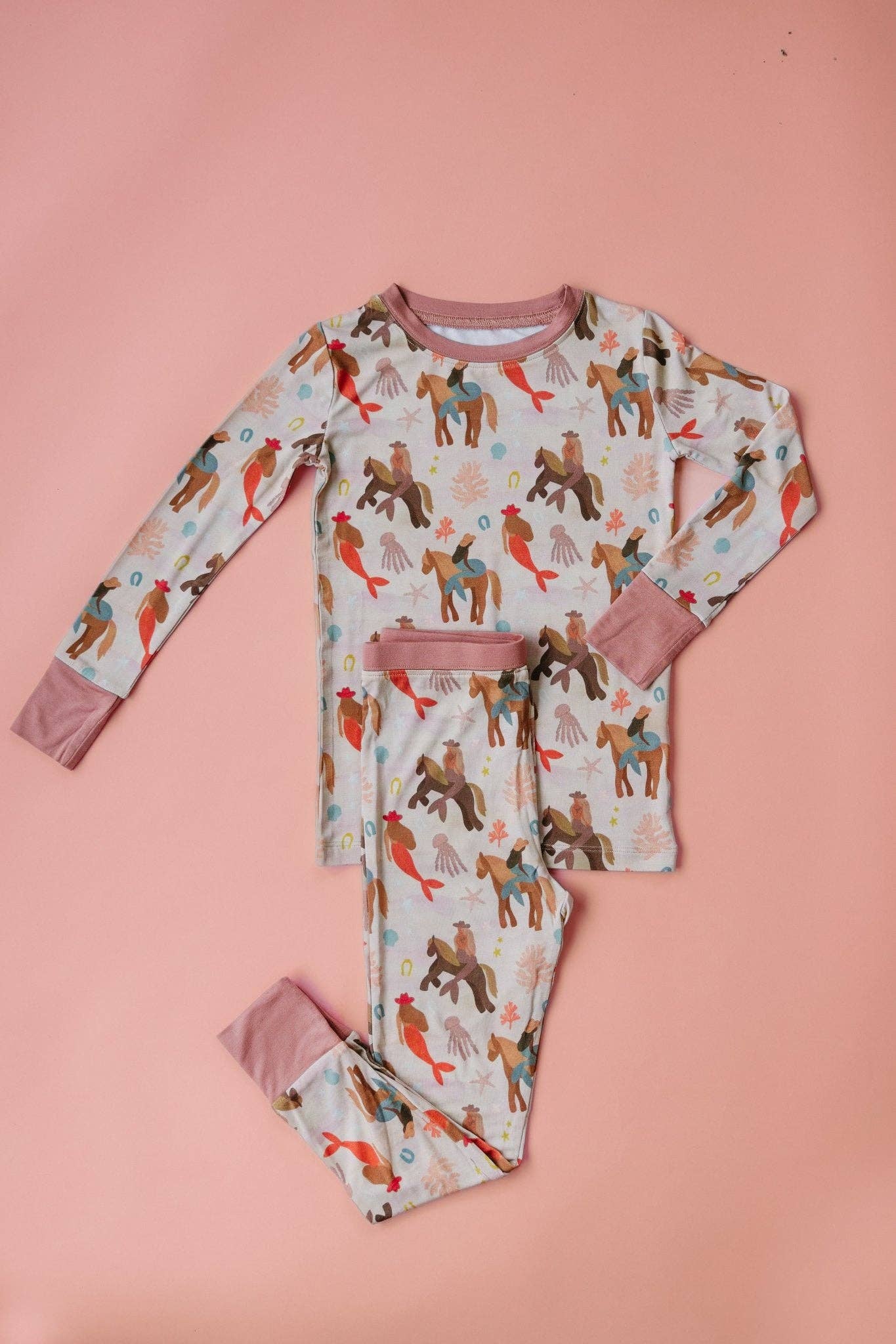 Children's pajama set with mermaid cowboy pattern on a pink background