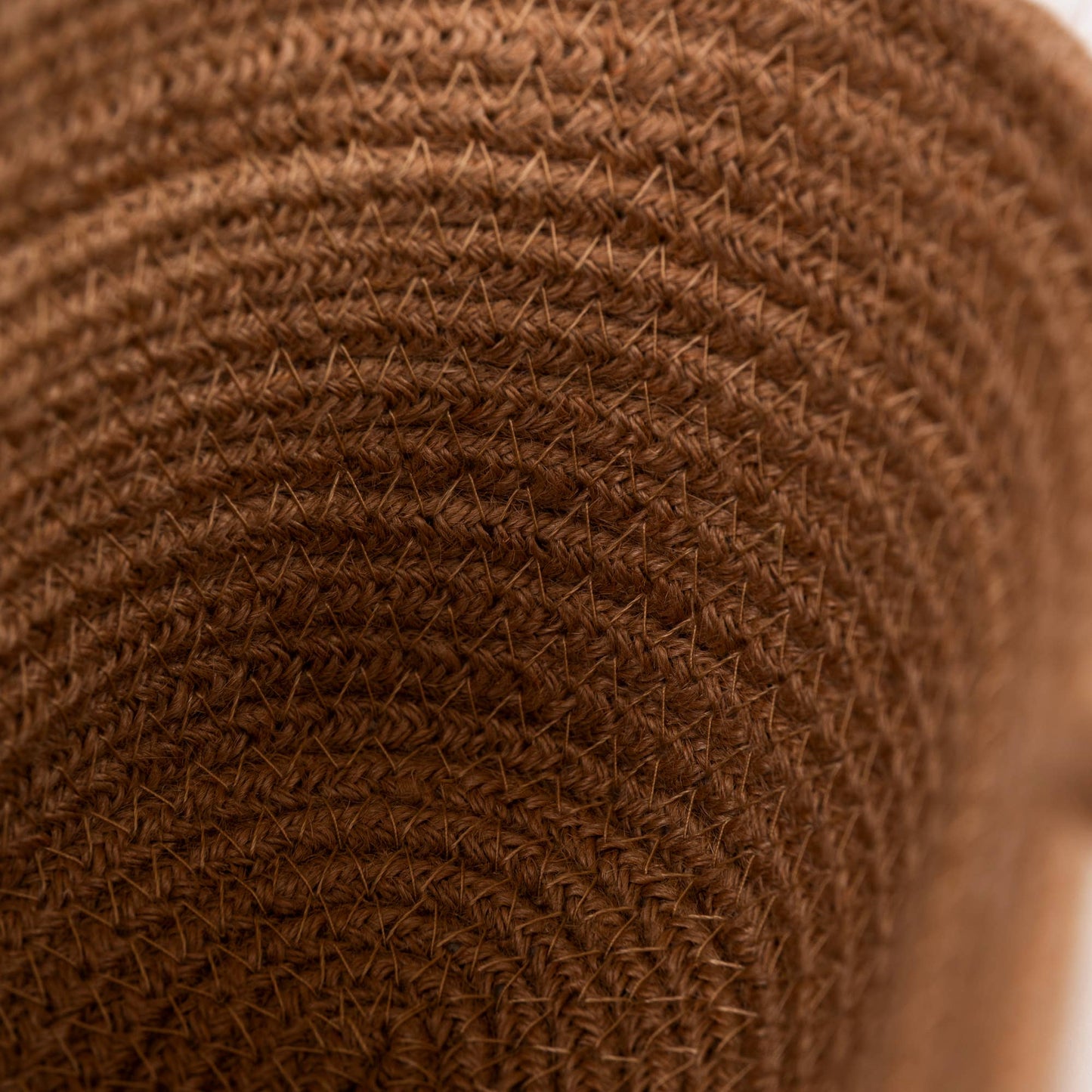 Close-up of a brown woven straw texture, likely showing the side of a sun hat or a rolled piece of straw material.
