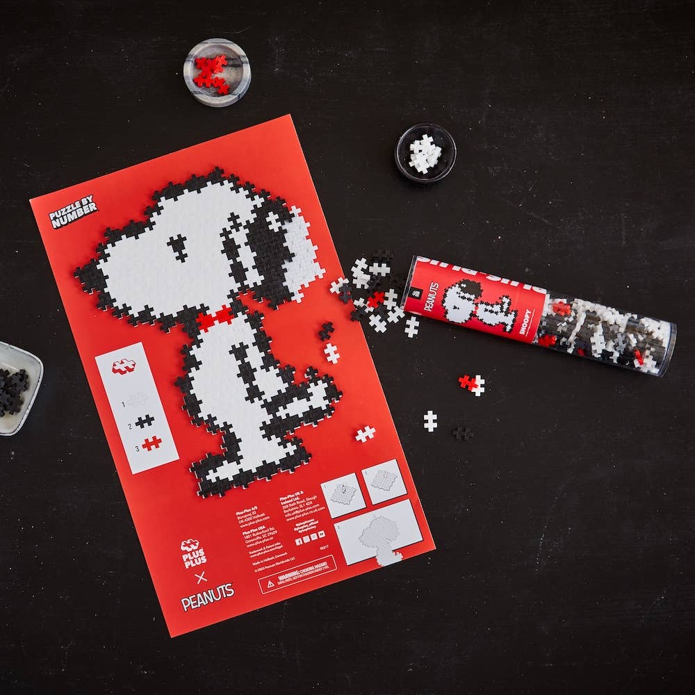 Peanuts-themed puzzle with packaging on a black surface