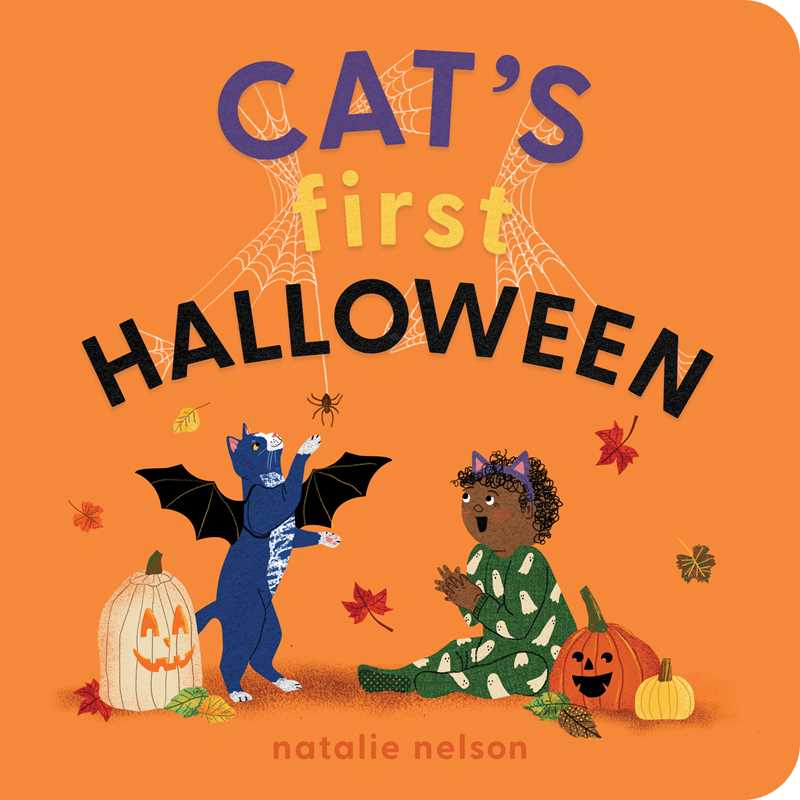 A hardcover children's book titled "CAT'S first HALLOWEEN" by Natalie Nelson, standing upright on a pale pink background. The cover is bright orange with playful Halloween illustrations including a blue cat in a bat costume, a child in a green spider costume, pumpkins, and spiderwebs.