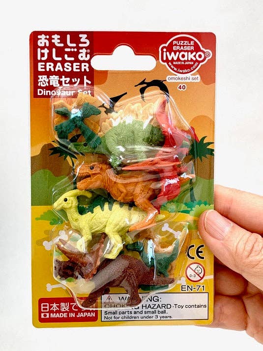 Packaged dinosaur eraser set with iwako branding held by a hand