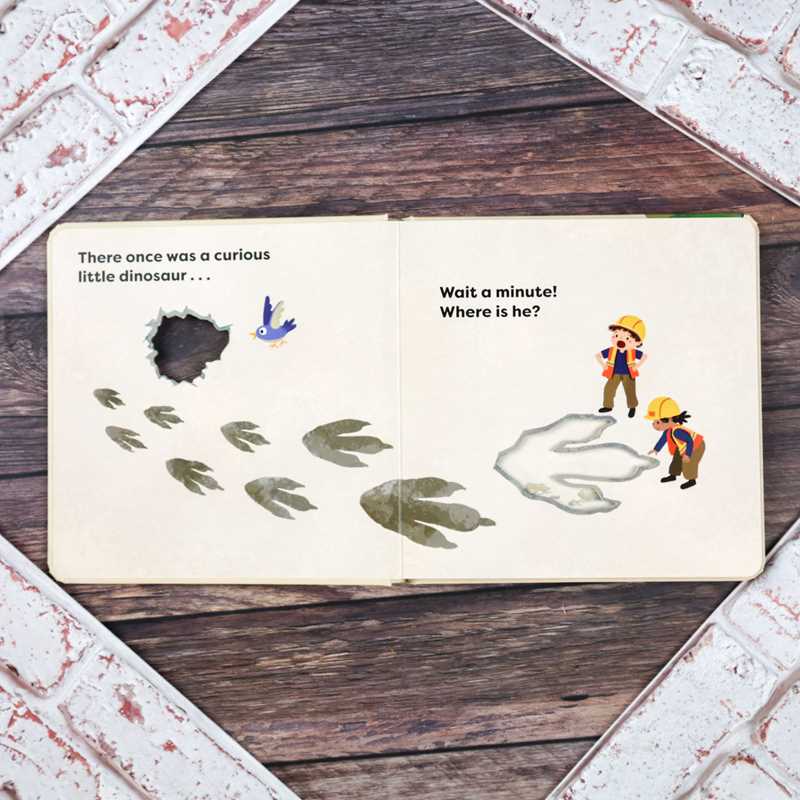 Open book with dinosaur-themed illustrations on a wooden surface