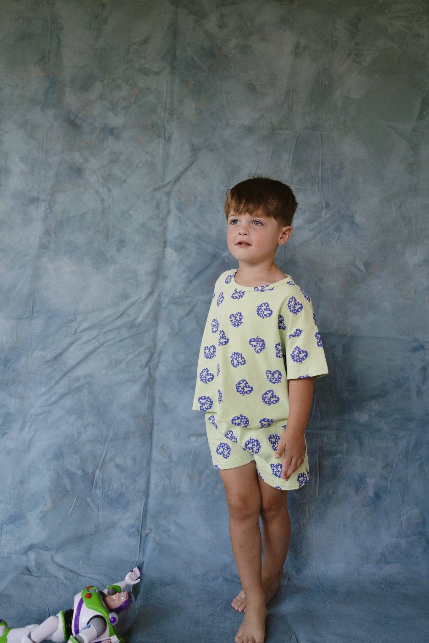 Child wearing a light-colored outfit with pretzel patterns against a textured blue background