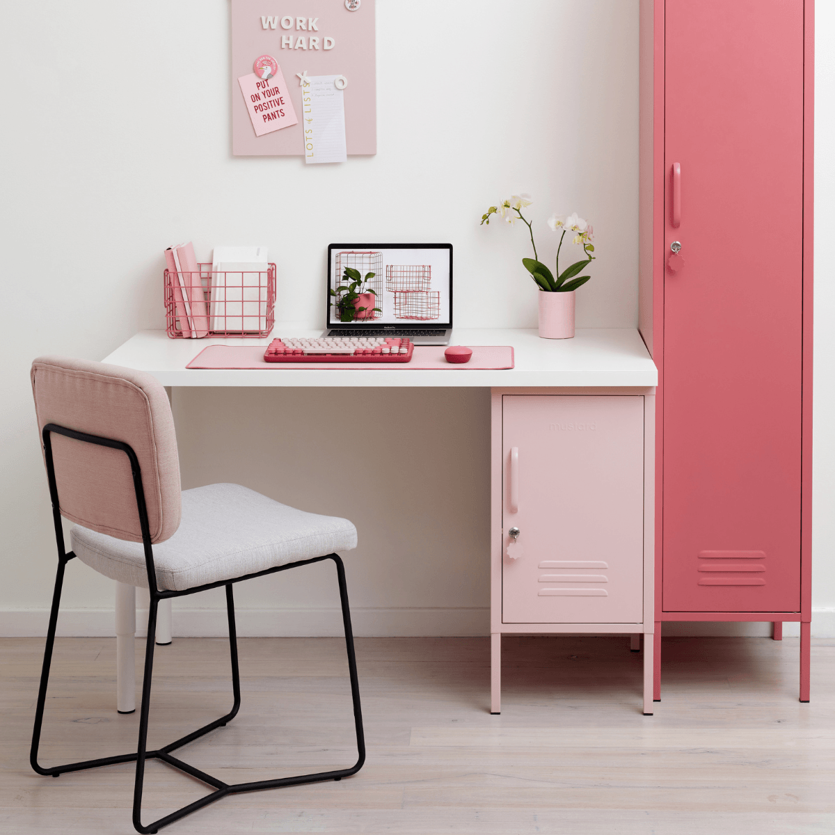 Pink desk with chair, laptop, and pink cabinet in a room.