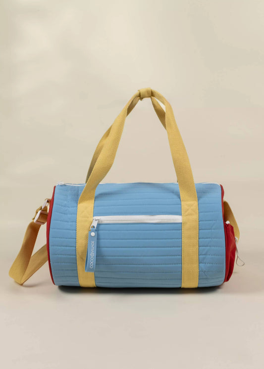 Multicolored duffel bag with blue, yellow, and red sections on a beige background