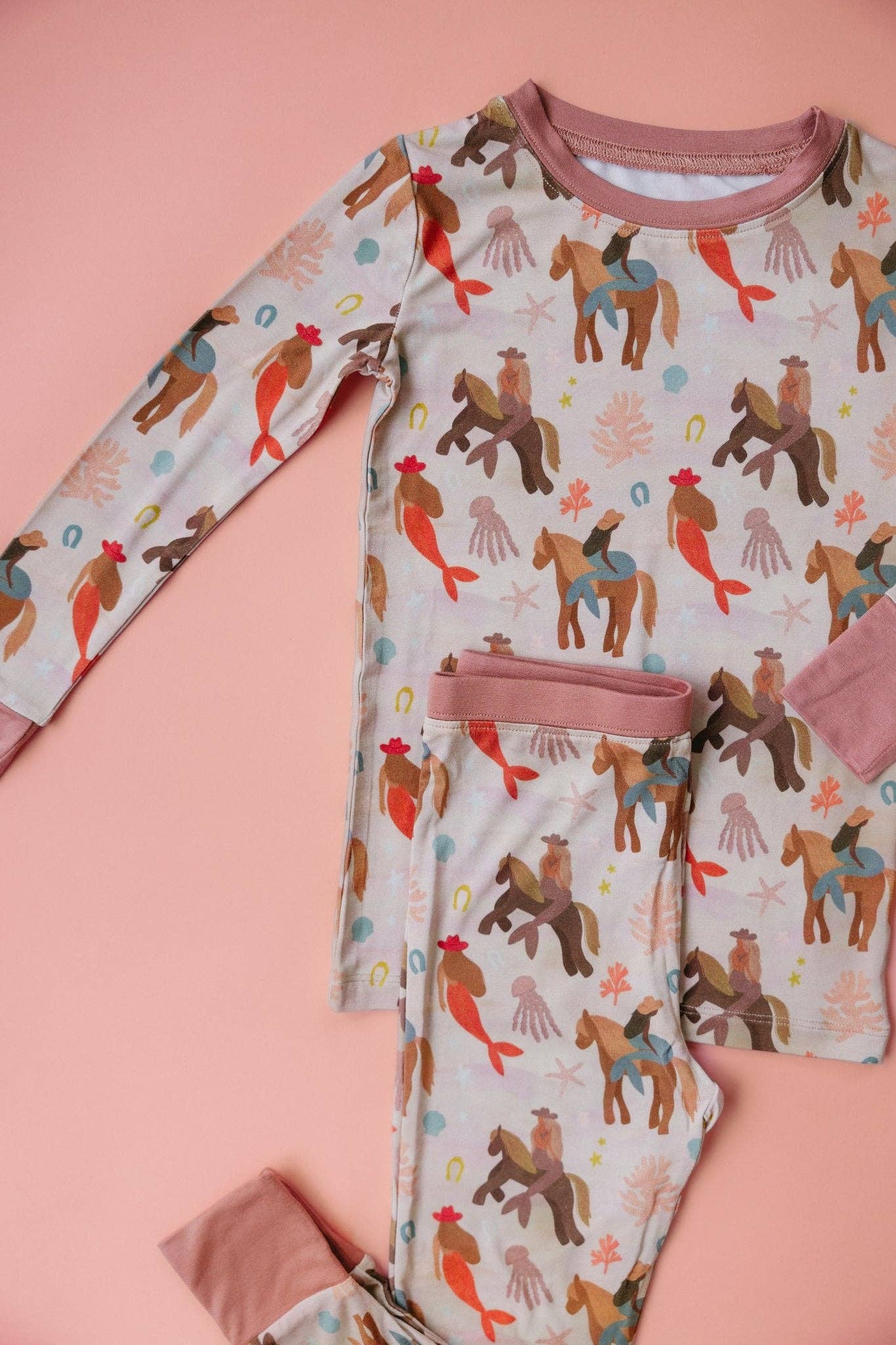 Children's pajama set with mermaid and horse pattern on a pink background