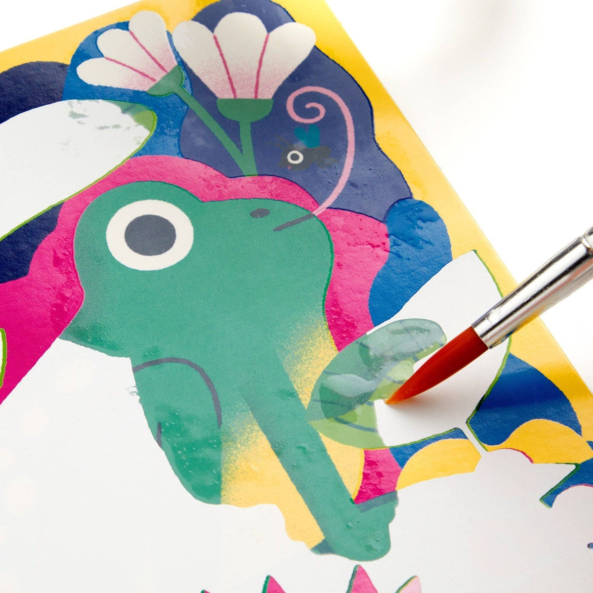 Colorful paper cutout of an elephant with a paintbrush applying red paint to it.
