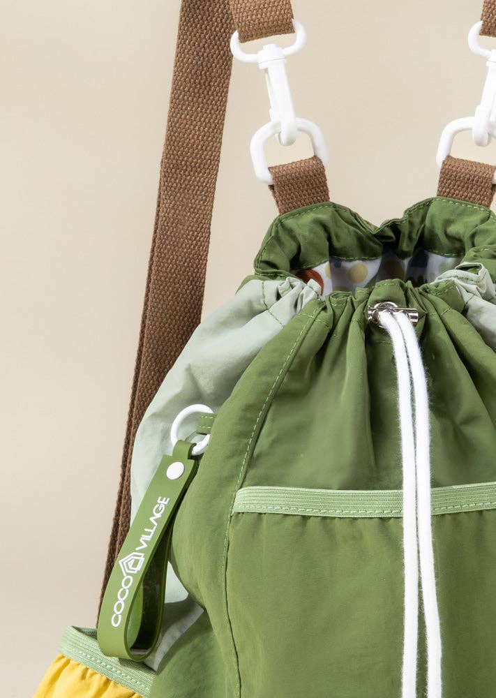 Green drawstring bag with a strap and yellow accents on a beige background