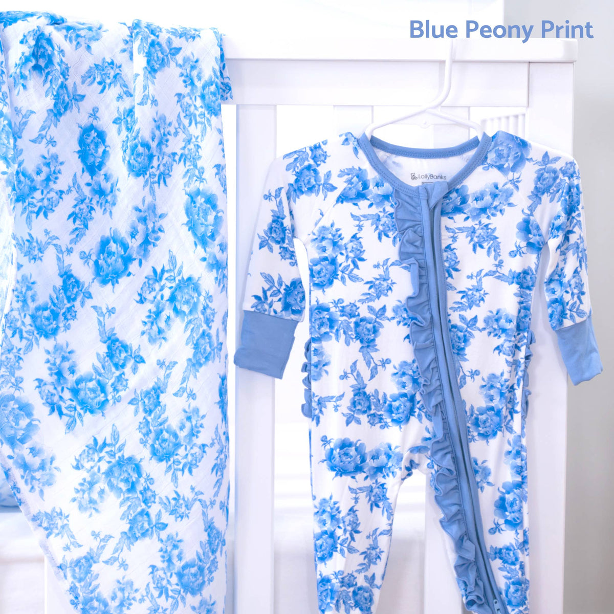 A baby footed one-piece sleeper and matching blanket set in a blue and white floral print, displayed on a white hanger stand. The text 'Blue Peony Print' is visible in the top right corner.