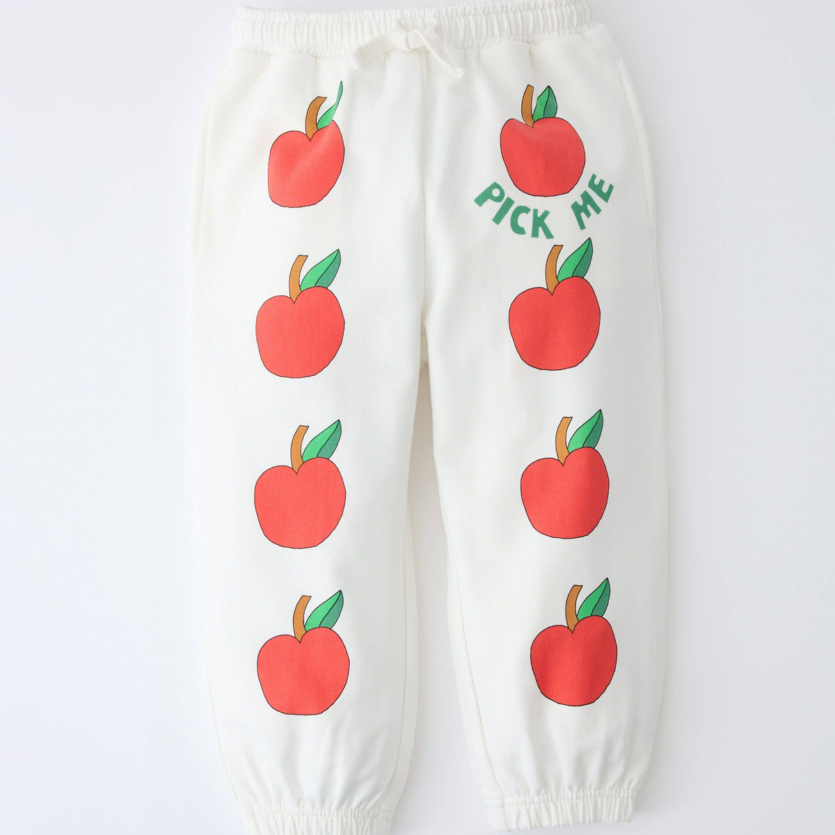 Off-white jogger pants with an all-over red apple print and the text 'PICK ME' on the right thigh, shown flat against a white background.