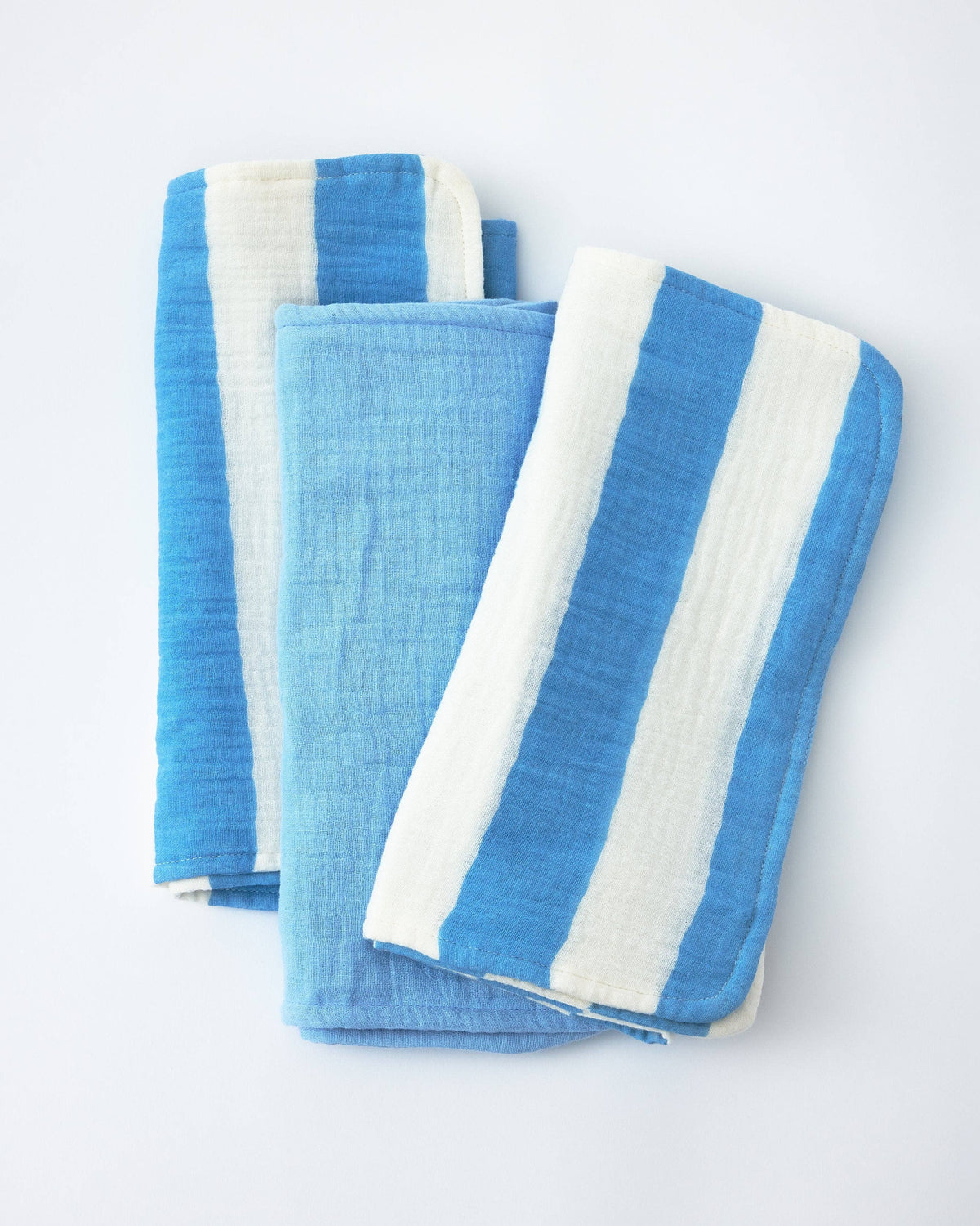 Three folded cotton muslin cloths with vertical blue and white stripes, arranged on a plain white background.