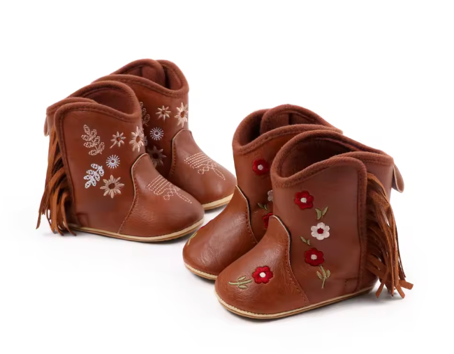 Pair of brown children's boots with floral embroidery and fringes on a white background