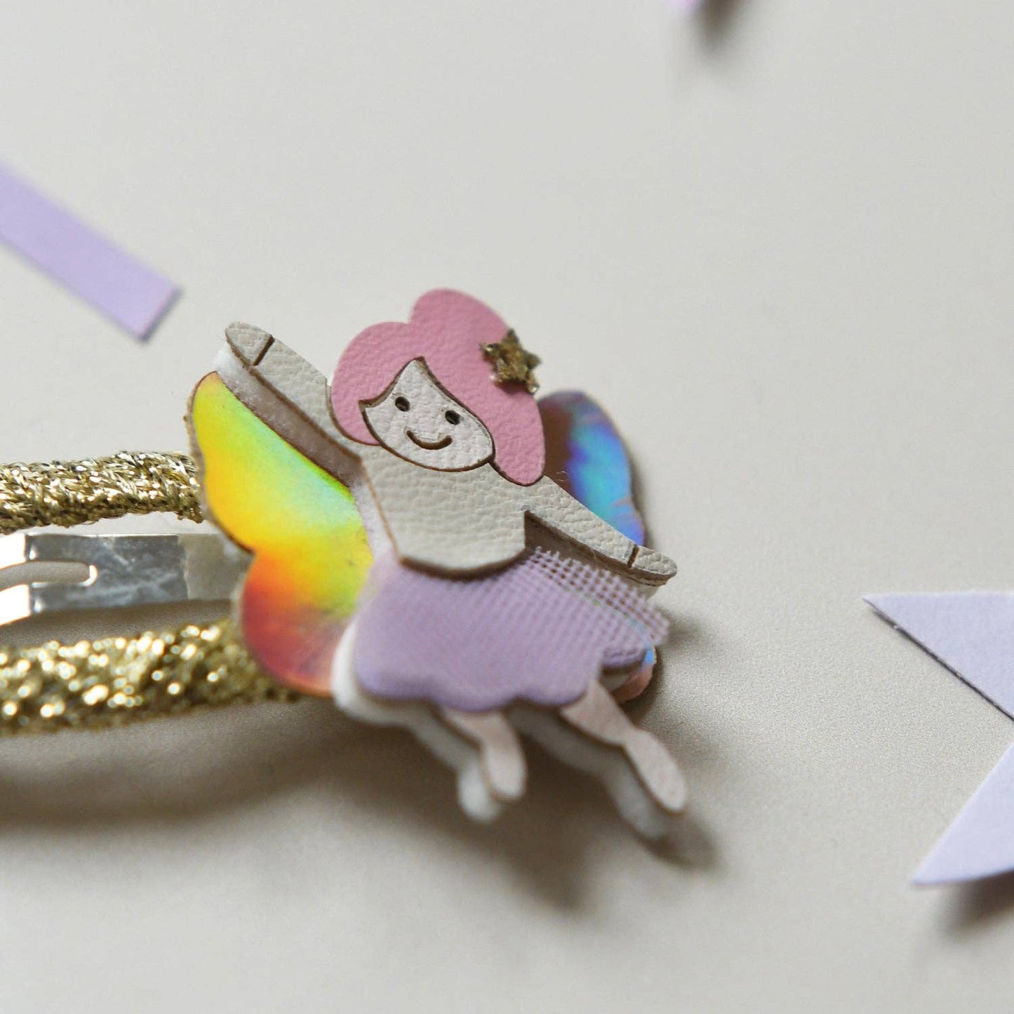 Wooden fairy ornament with pink hair and rainbow wings on a light background