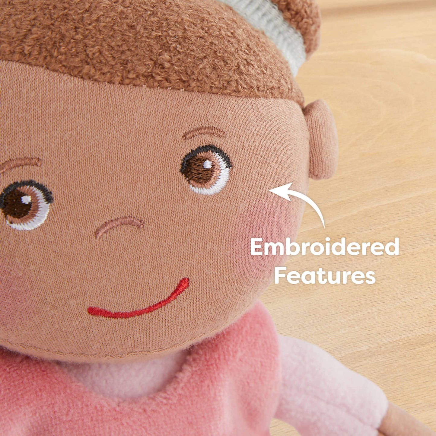 Close-up of a plush toy with embroidered features on a wooden surface