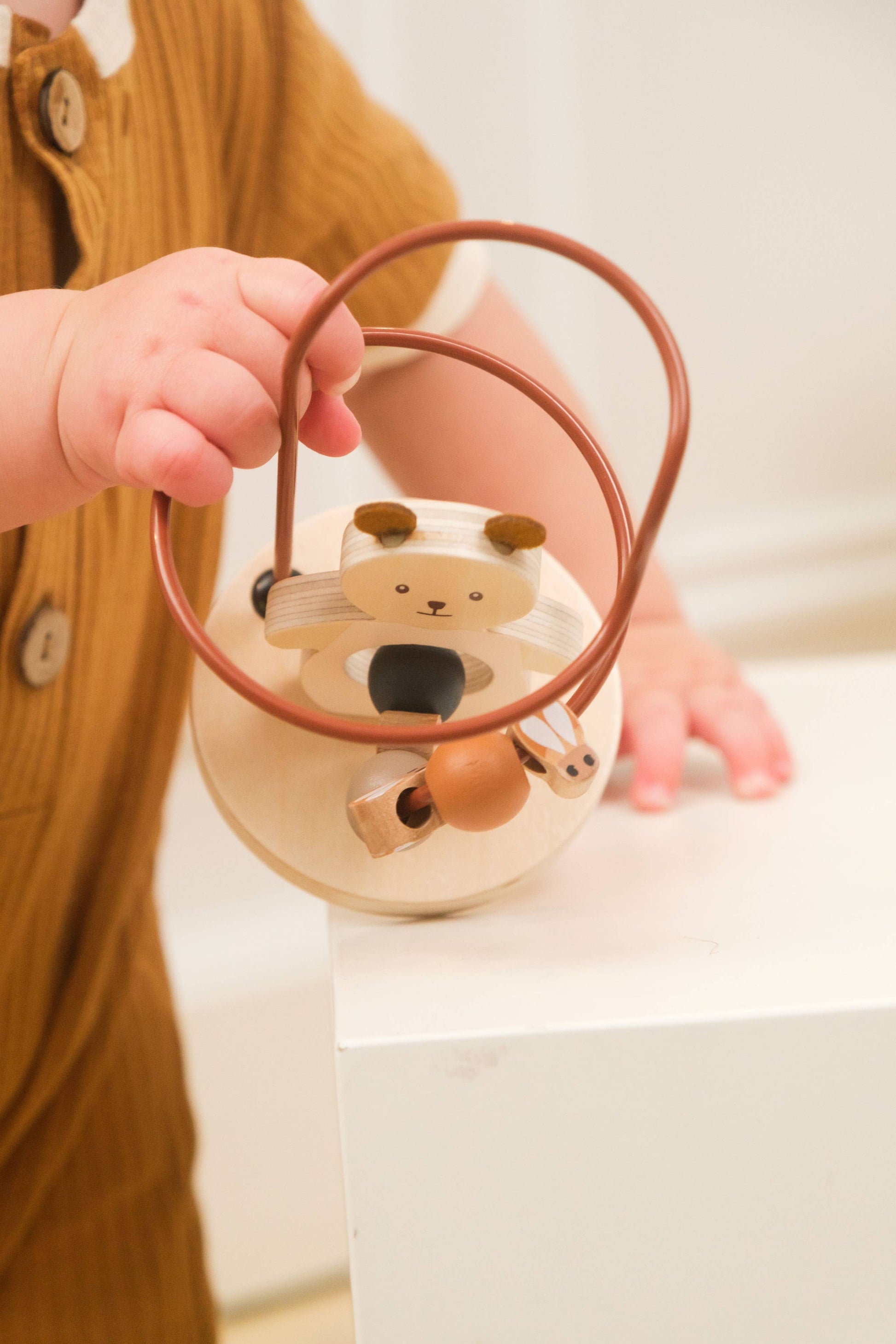 Child holding a small bear-shaped lantern with a brown handle.