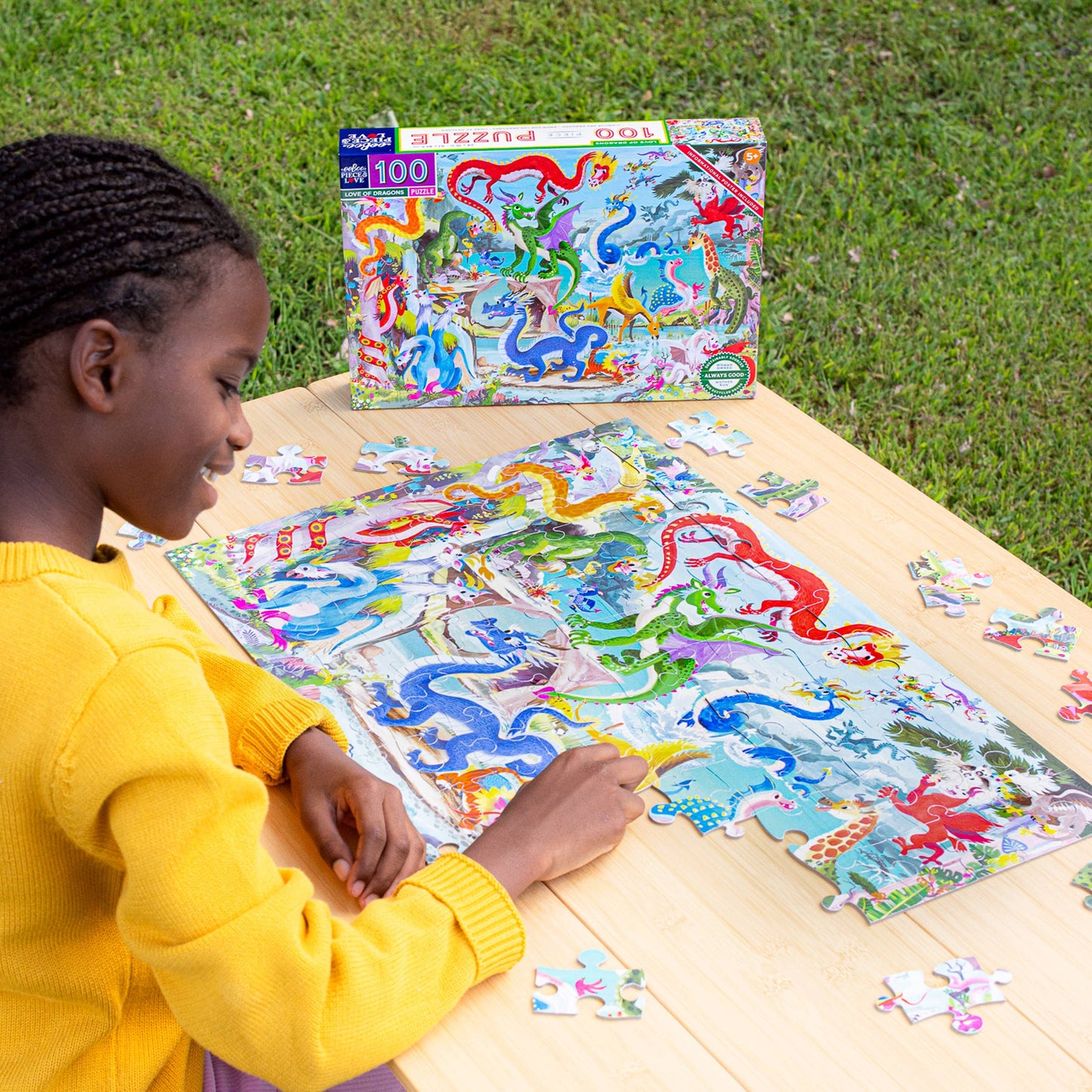 Child working on a dinosaur-themed puzzle outdoors with the puzzle box in the background.