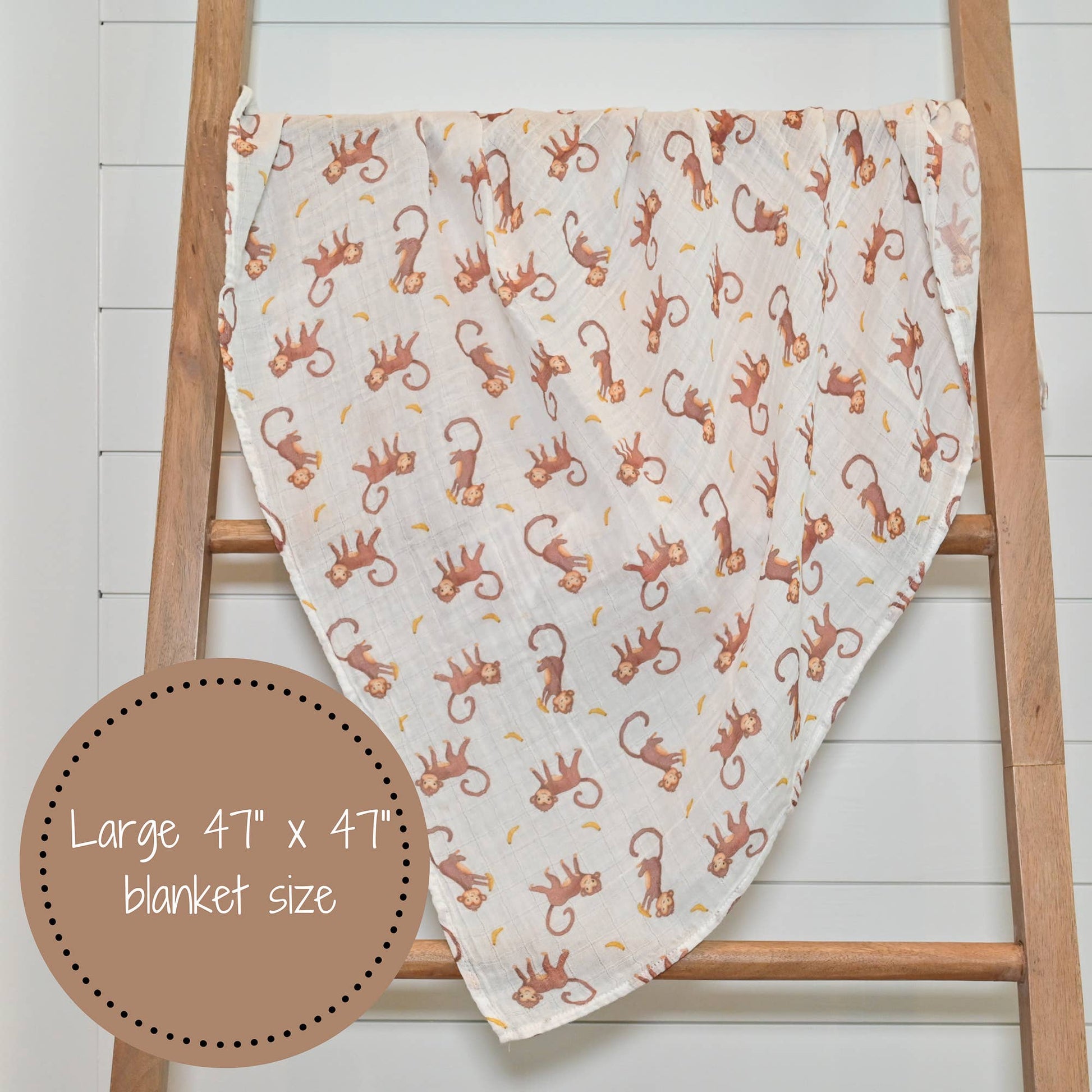 Blanket with monkey pattern draped over a wooden ladder on a white background
