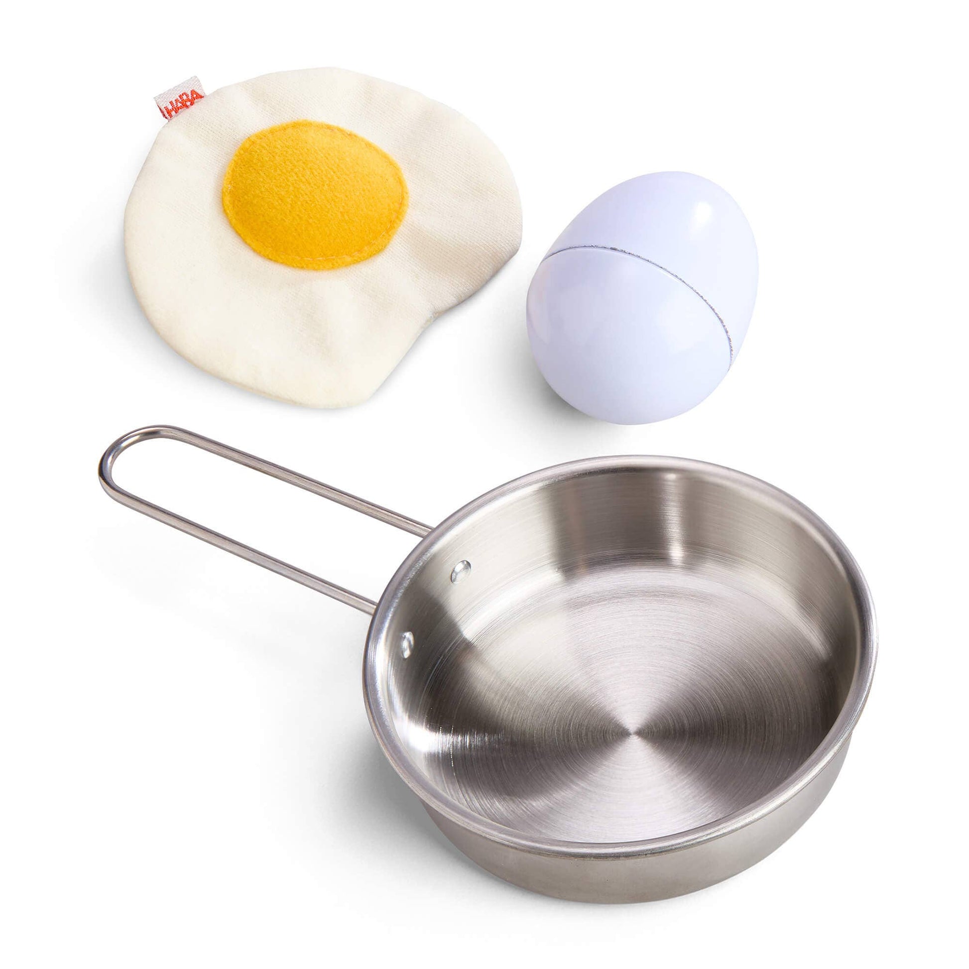 Stainless steel frying pan with a fried egg-shaped object and a white sphere on a white background