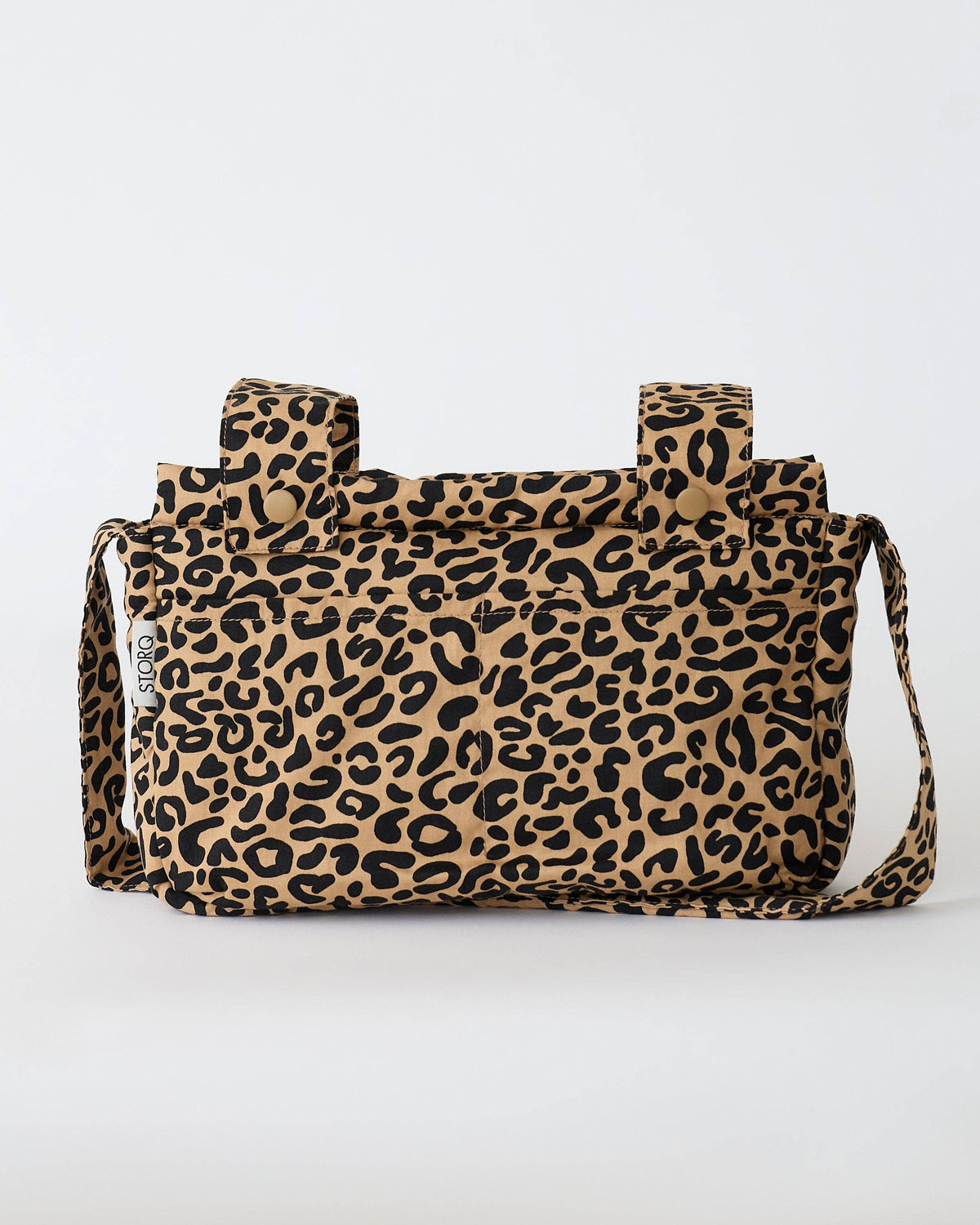 A leopard print canvas stroller bag with a tan background, black spots, and a matching shoulder strap, shown against a plain white background.