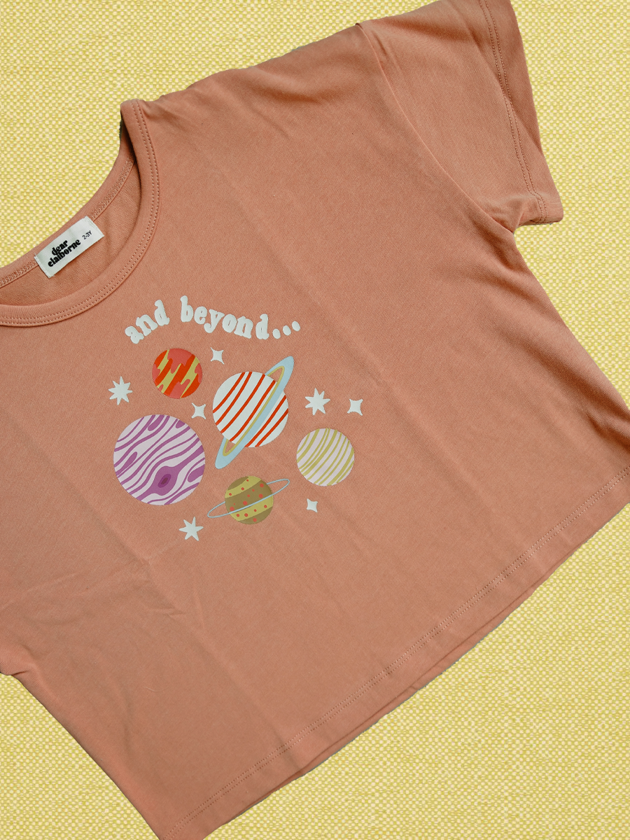 Orange t-shirt with space-themed graphic and 'and beyond...' text on a yellow background