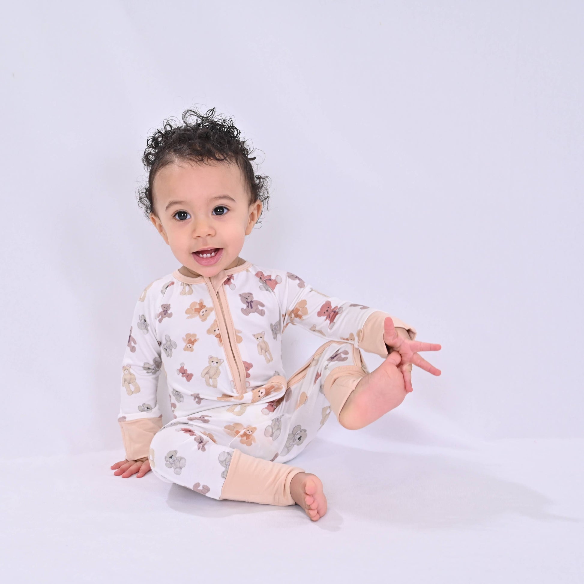 Baby wearing teddy bear pajamas on a white background