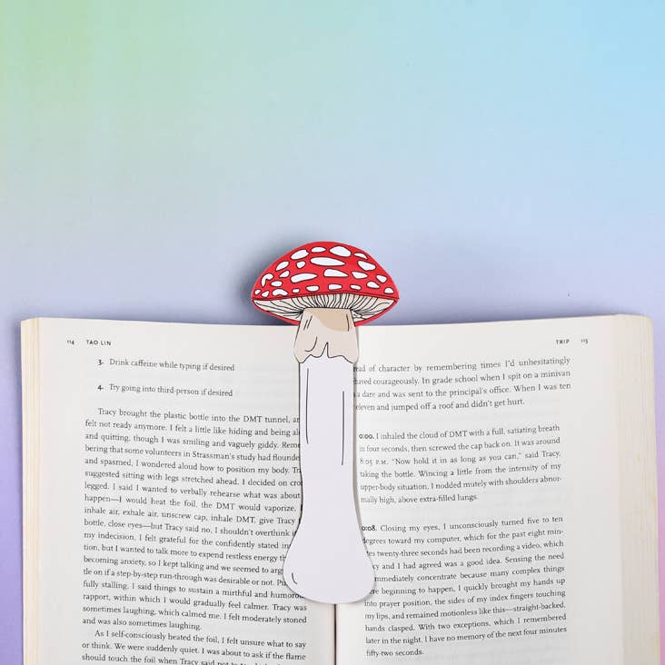 Mushroom-shaped red and white bookmark on an open book with a colorful gradient background
