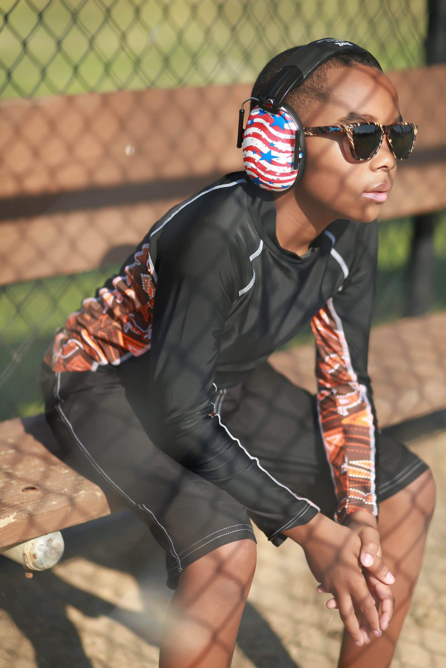 Person wearing headphones and sunglasses sitting on a bench.