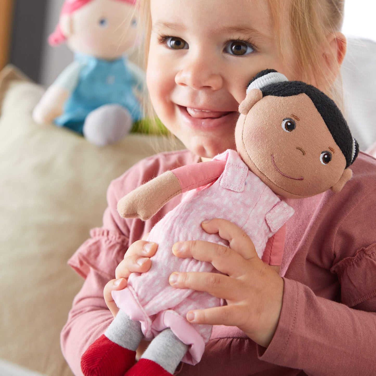 Child holding a plush doll with a neutral background