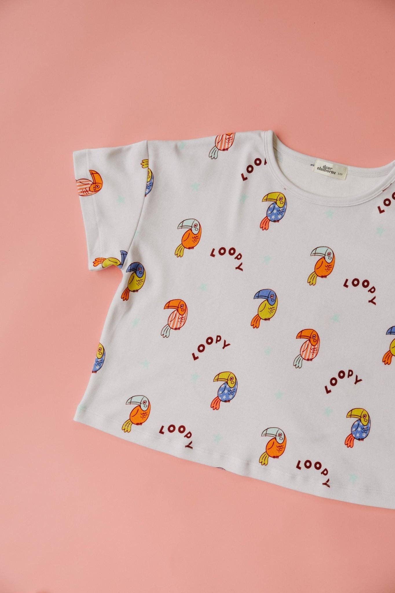 White t-shirt with colorful toucan prints on a pink background