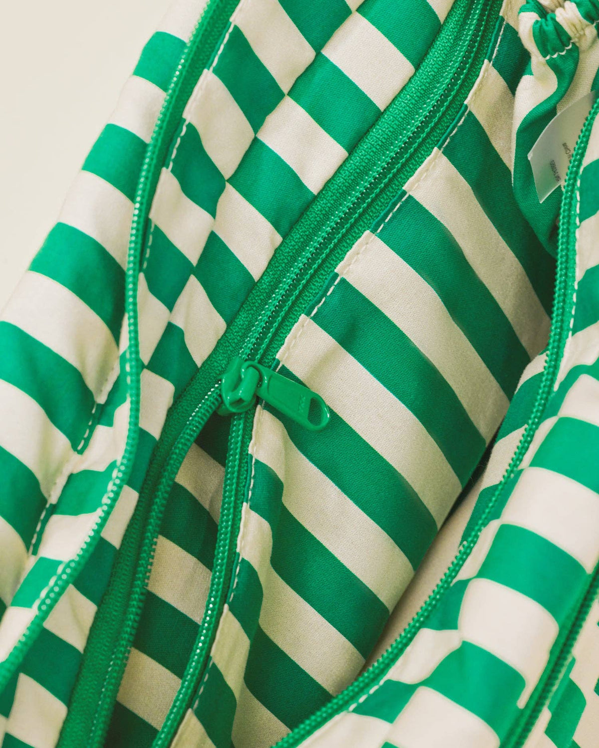 Close-up of a green and white striped garment with a zipper.