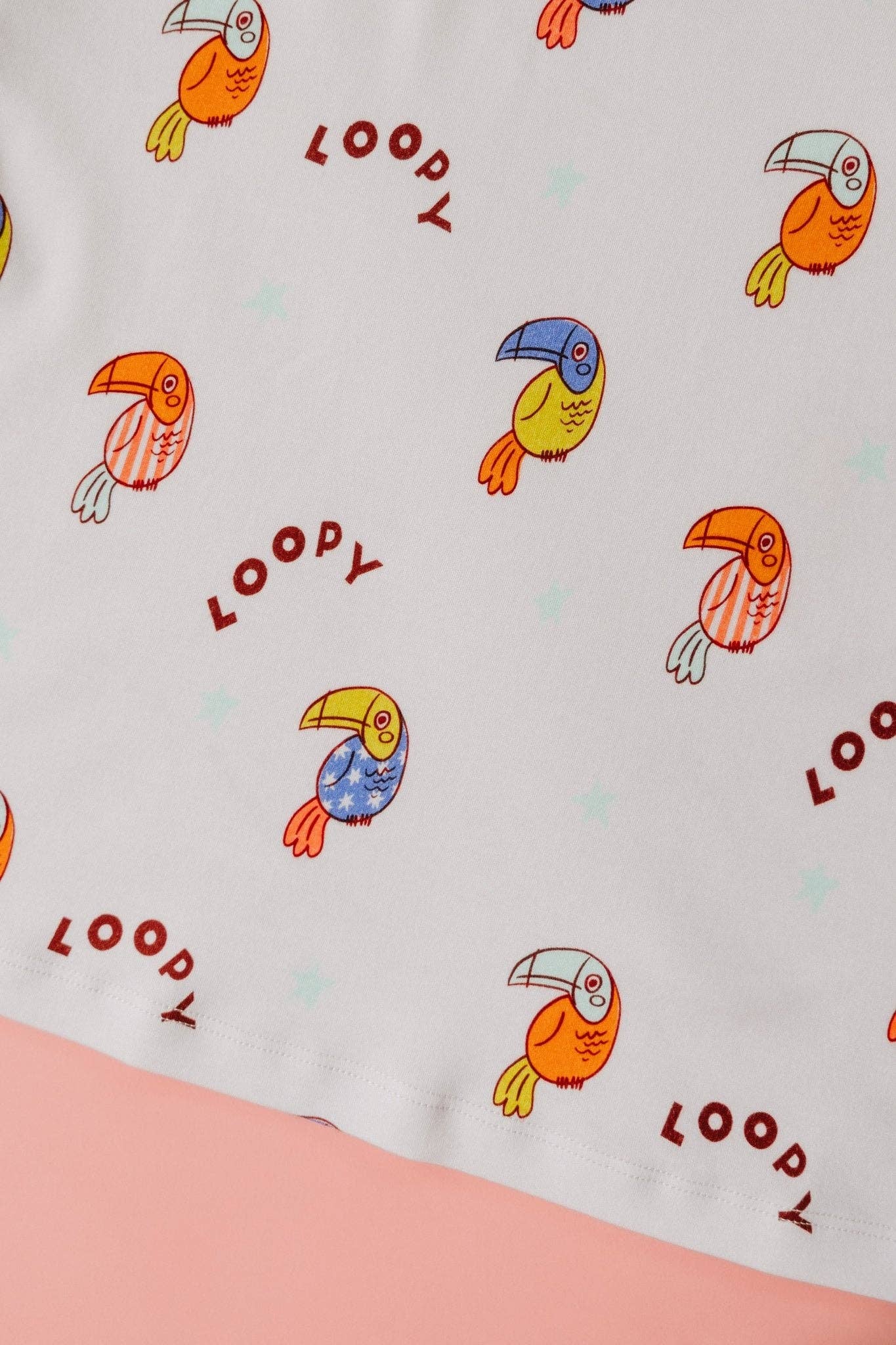 Fabric with colorful toucan patterns and 'LOOPY' branding on a light background.