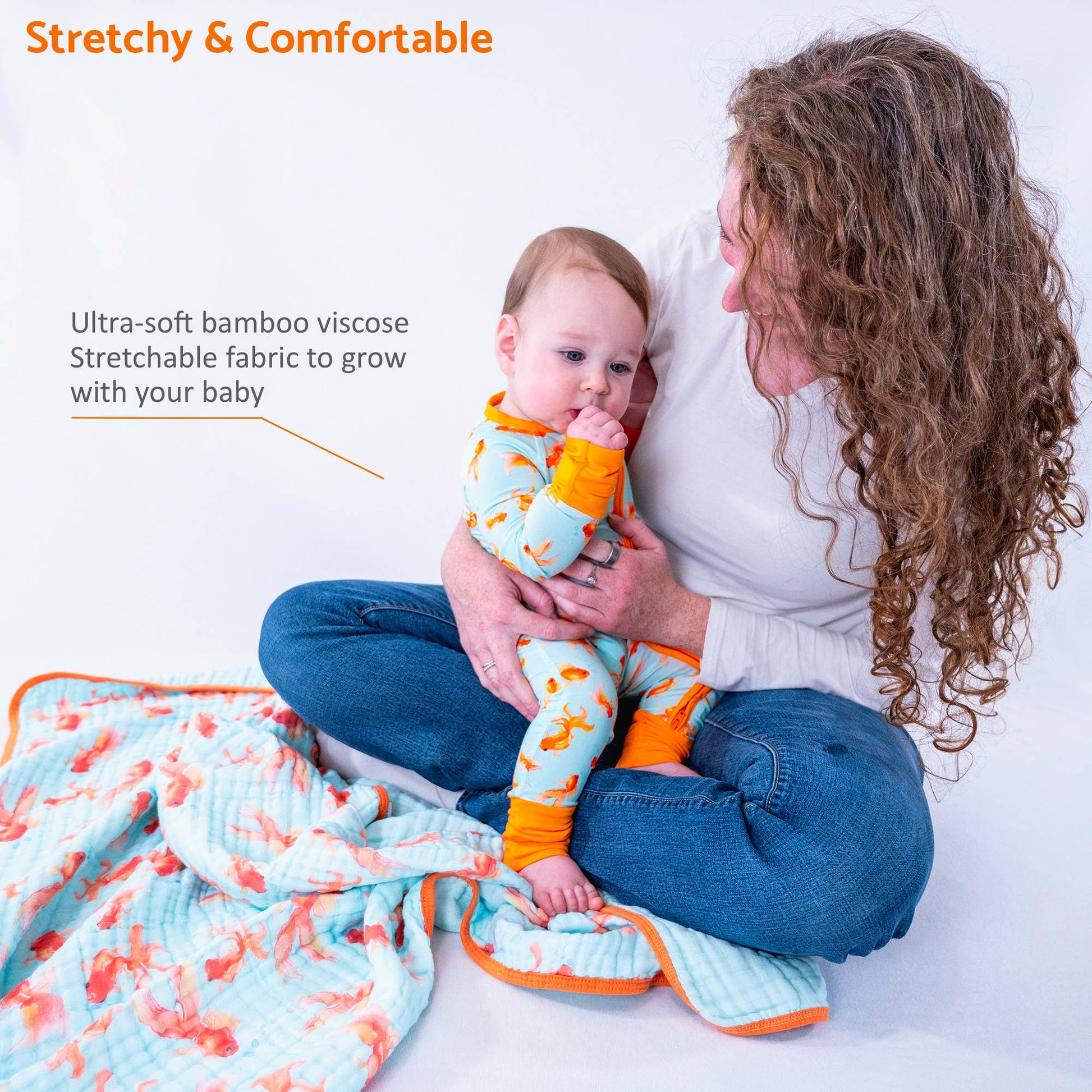 Woman holding a baby wearing colorful pajamas with text about stretchy and comfortable fabric.