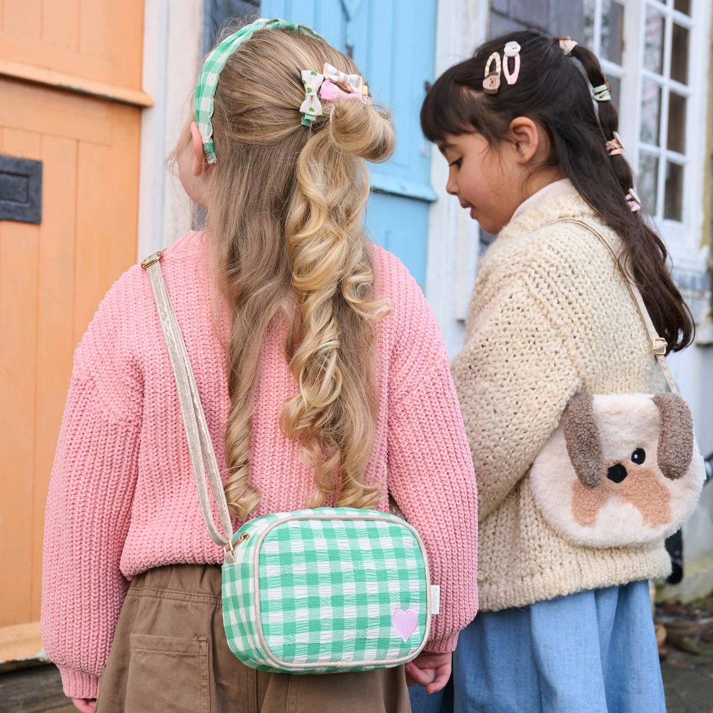 Two children with styled hair and colorful bags standing next to each other.