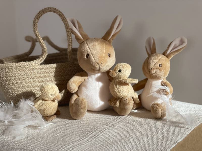 Set of plush bunnies and a basket on a textured surface