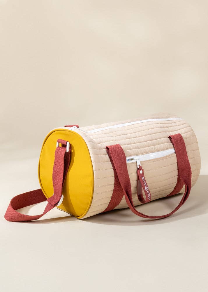 Round bag with yellow top half and beige bottom half on a beige background